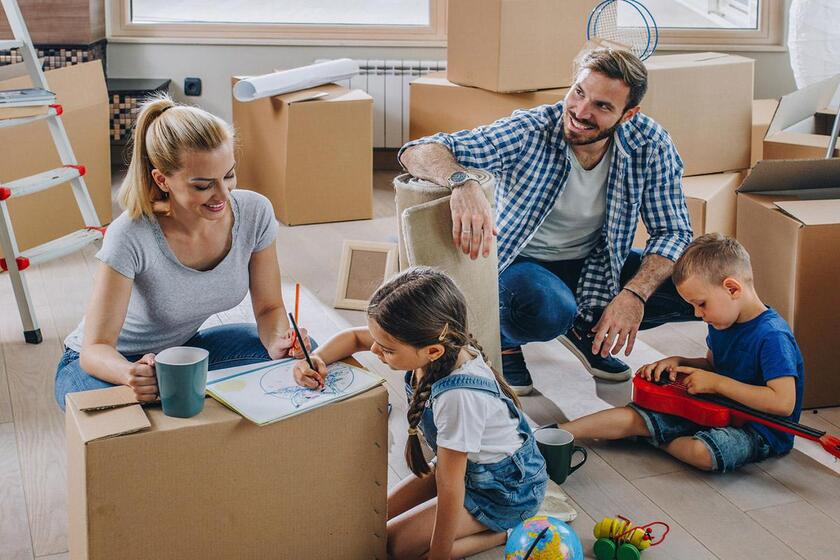 dzieci bawiące się w salonie z rodzicami w trakcie przeprowadzki